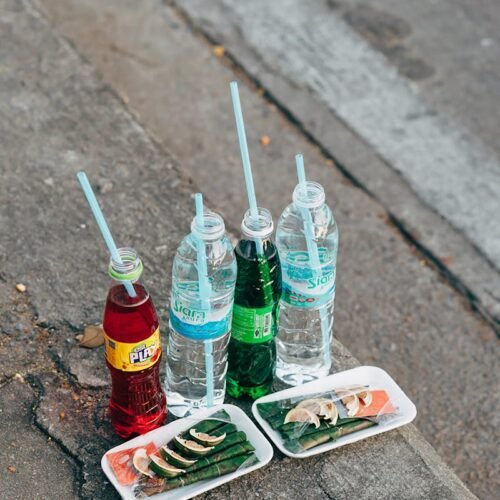 Traditional Thai offerings with drinks and snacks laid out on a Bangkok street sidewalk.