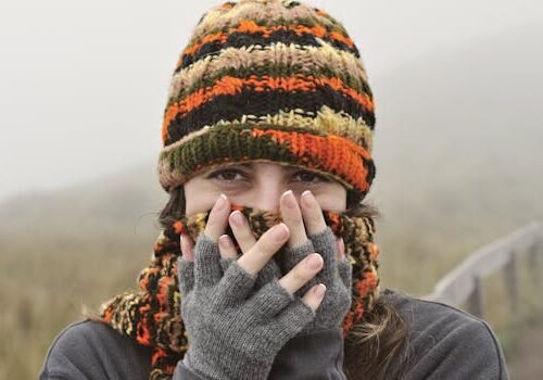 A woman wears knitted hat and gloves in a foggy Ecuadorian landscape, capturing a cozy winter feel.