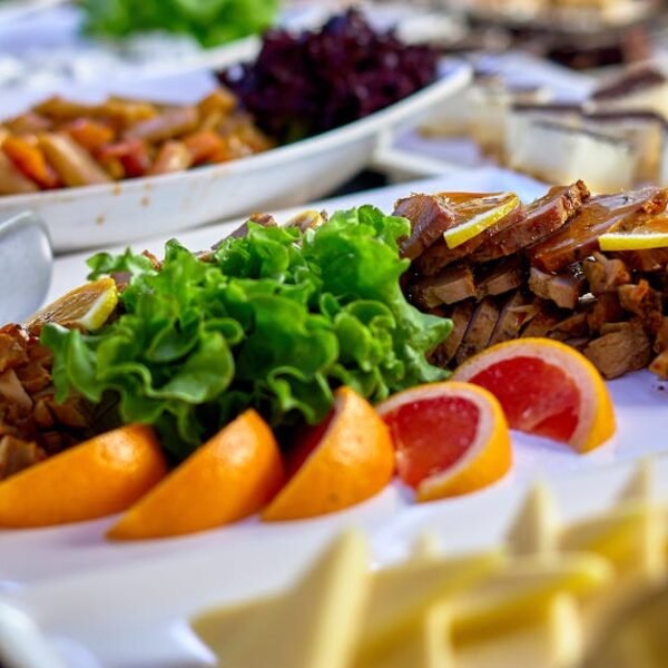 A vibrant buffet spread featuring sliced meats, fresh greens, and juicy citrus fruits on a serving board.