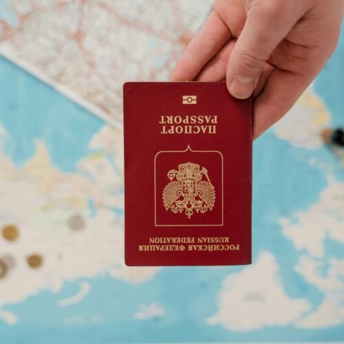 A hand holding a Russian passport over a map, suggesting travel preparation.